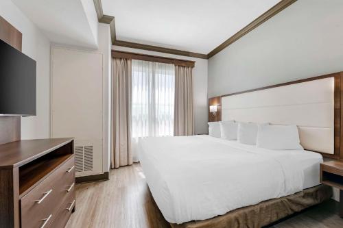 尤利贝斯特韦斯特Plus第一海岸套房酒店的卧室配有一张白色大床和电视。
