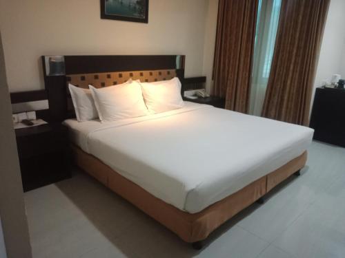 安汶马尼斯酒店的一张带白色床单和枕头的床
