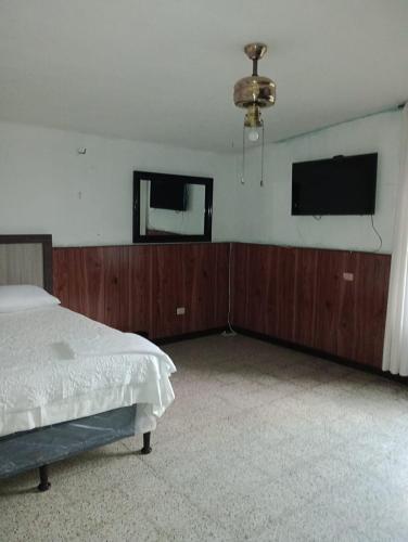 危地马拉MUNDO HOSTAL的一间卧室配有一张床和一台平面电视
