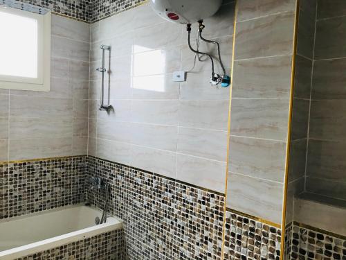 伊斯梅利亚Chalets and apartments Al-Nawras Village Ismailia的带浴缸的浴室和瓷砖墙壁。