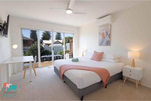 沃纳姆堡Botanic Beach的一间卧室配有一张床、一张书桌和一个窗户。