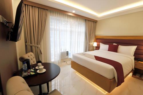 TaytayMonaco Hotel的酒店客房配有一张床铺和一张桌子。