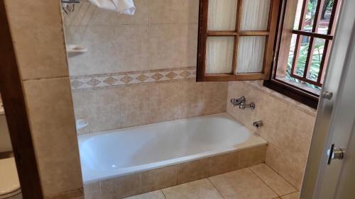 伊瓜苏港Hotel Cabañas del Leñador的带窗户的浴室内的白色浴缸