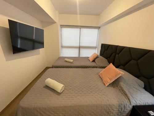 利马Monterrico Polo Aparts - Cerca a la Embajada de USA的一间卧室配有两张床和一台平面电视