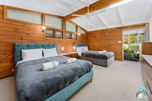 TuggerahAircabin - KANGY ANGY - Rural Retreat - 8 Beds House的一间带两张床铺的卧室,位于带木墙的房间内