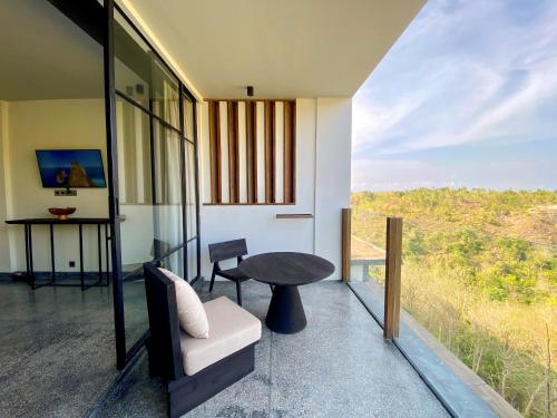 珀尼达岛MAUA Nusa Penida Bali的带阳台的客房配有桌子和椅子
