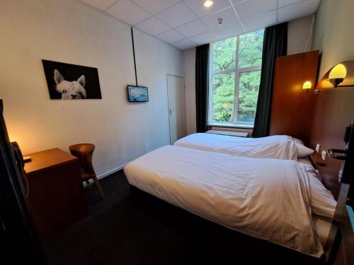 HoevenConferentiecentrum Hotel Bovendonk的酒店客房设有两张床和窗户。