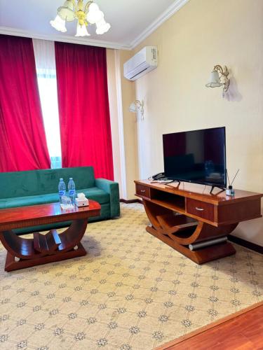 塔拉兹Luxurious的客厅配有绿色沙发和电视