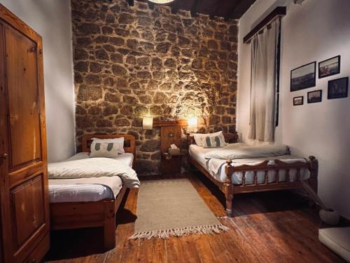 库塞尔El Quseir Hotel的一间设有两张床和石墙的房间
