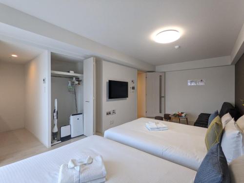 大阪ESLEAD HOTEL Osaka Nipponbashi的一间酒店客房,设有两张床和电视