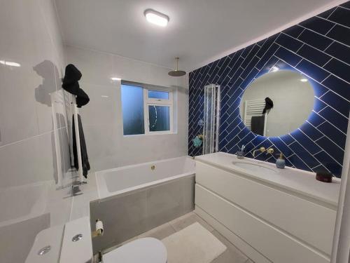 卡里格莱恩Carrigaline Delightful Home的带浴缸、卫生间和镜子的浴室