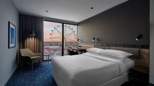 墨尔本Vibe Hotel Melbourne Docklands的酒店客房设有一张白色大床和一张书桌