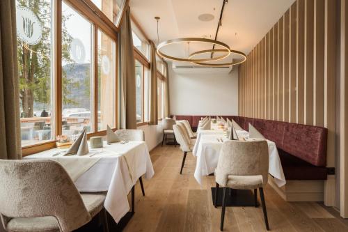 哈尔施塔特哈尔施塔特历史酒店的餐厅设有白色的桌椅和窗户。