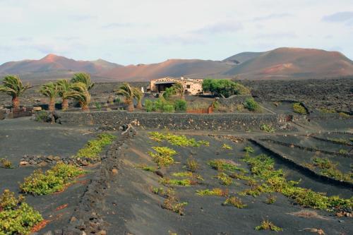 UgaCasa Rural Vega de Timanfaya的沙漠中的村庄,以群山为背景