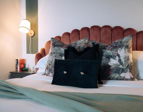 韦茅斯Pebble View - Central Cosy with Sea-Views的一张带黑色枕头和红色床头板的床
