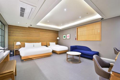 釜山Seomyeon IB Hotel的一间卧室配有两张床和蓝色的沙发
