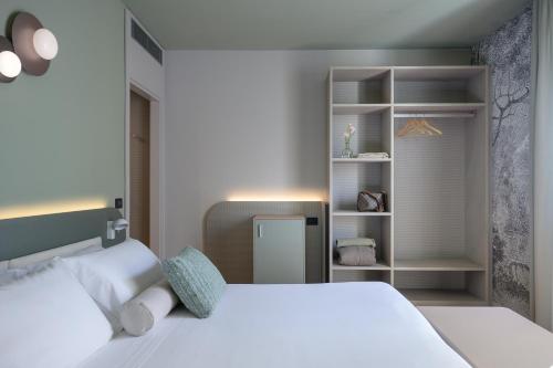 卢卡Hotel Ilaria的卧室配有白色的床和书架