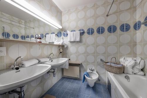 巴德小基希海姆圣奥斯瓦尔德酒店的浴室配有2个盥洗盆、卫生间和浴缸。