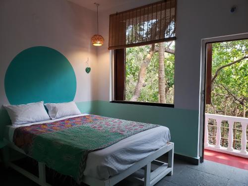 QuerimAdi Shakti Guesthouse的一间卧室配有一张带绿色床头板的床和两个窗户