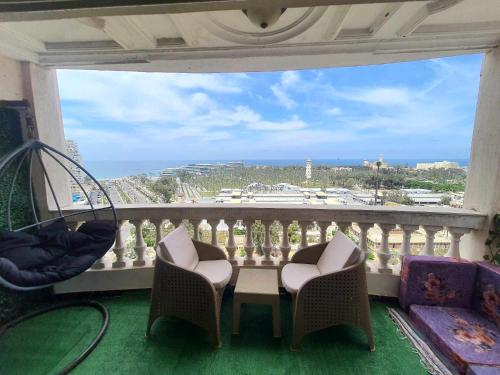 亚历山大Sea and Montaza Palace view 2 bedrooms apartment alexandria,2 full bathrooms, with 2 AC and 1 Stand Fan, wifi, 4 blankets available的设有一个配有桌椅并享有美景的阳台。