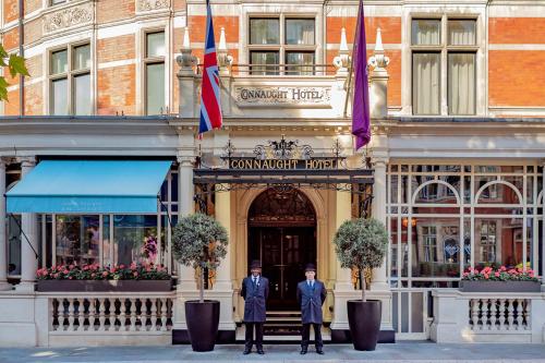 伦敦梅宝尼康诺酒店的站在建筑物前身的两名穿着西装的男子