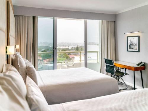悉尼Novotel Sydney Brighton Beach的酒店客房配有两张床和一张书桌