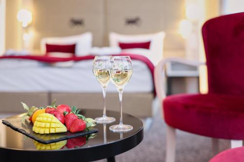 苏黎世圣哥特哈尔德酒店的在酒店房间桌子上放两杯葡萄酒和水果
