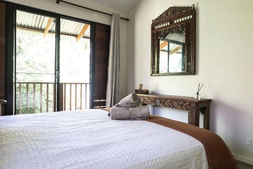 拜伦湾Warung Guest House Byron Bay的卧室配有一张壁挂镜子的床
