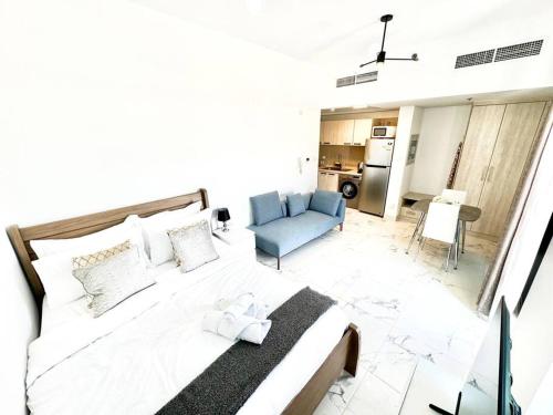 迪拜Mag 5 Spacious studio apartment的卧室配有一张白色大床和一张蓝色沙发。