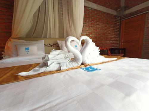 KubutambahanCoco Garden Pool Villas的两只天鹅用毛巾制成,坐在床上