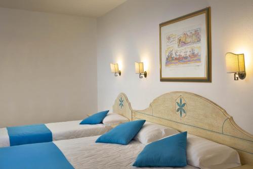 卡拉·利贝罗托Hotel Villa Campana的两张位于酒店客房的床,配有蓝色枕头