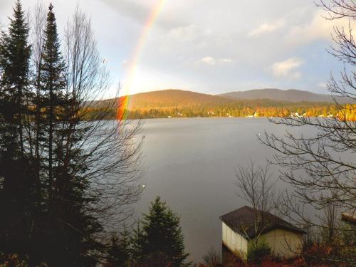 苏必利尔湖Chalet Le Pélican的一座有房子和建筑的湖上空的彩虹