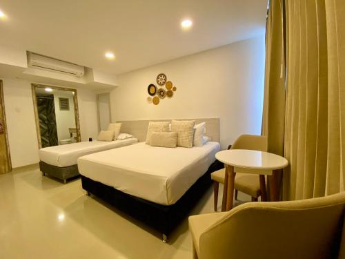 卡塔赫纳Hotel Dorado Plaza Bocagrande的酒店客房设有两张床和一张桌子。