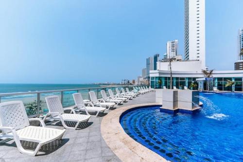 卡塔赫纳Apartamento con vista al mar piso 19 Bocagrande的游泳池旁的一排白色椅子
