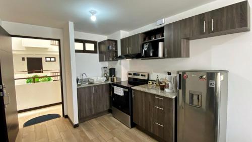 危地马拉Apartamento en centro Ciudad de Guatemala z12的厨房配有木制橱柜和不锈钢冰箱。