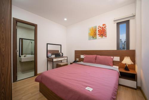 岘港S HOTEL BEACH ĐÀ NẴNG的卧室配有粉红色的床和镜子