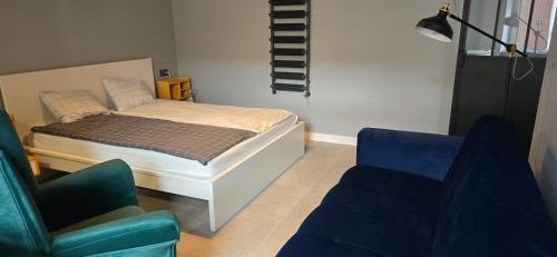 普沃茨克Apartamenty STARA PIEKARNIA的一间卧室配有一张床、两把椅子和一张沙发