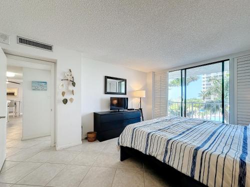 马可岛Beach Front Condo In Paradise Marco Island的一间卧室设有一张床、一台电视和一个窗口。