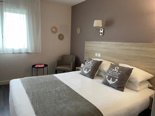 莱萨布勒-多洛讷Cit'Hotel Le Chêne Vert的一间卧室配有一张大床和一把椅子