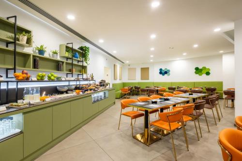 米兰IH Hotels Milano Centrale的餐厅设有绿色柜台、桌子和橙色椅子