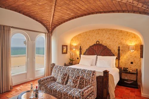卡斯卡伊斯Hotel Fortaleza do Guincho Relais & Châteaux的一间卧室配有一张床、一张沙发和一个窗口