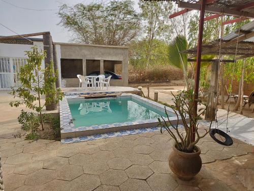 NdanganeLa Maison Blanche的庭院内带桌椅的小游泳池
