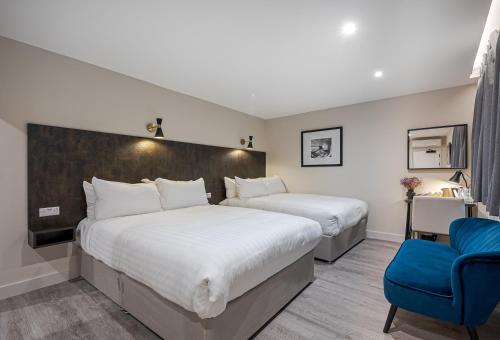 伦敦Kings Cross Express Hotel的两张位于酒店客房的床,配有蓝色椅子