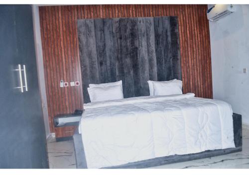 阿布贾Empire Suites And Apartment的卧室配有白色的床和木制床头板