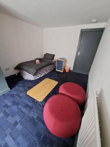 凯格沃思Room near East Midland Airport Room 7的一间设有床铺和红色凳子的房间