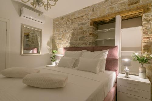 特罗吉尔Sobe Bartul Trogir的卧室配有一张白色大床和石墙