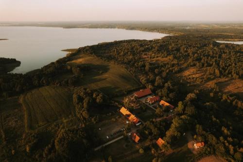 吉日茨科Poganty - Jałownik的享有湖畔小山上农场的空中景色
