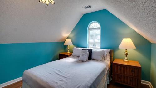 萨凡纳Mins to Savannah-Peachy Pied-à-Terre的一间卧室设有蓝色的墙壁和一张带窗户的床