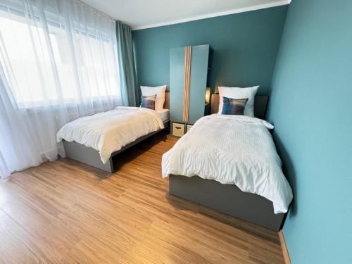 马尔JUNX Bude的卧室设有两张床,拥有蓝色的墙壁和木地板