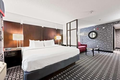 威廉斯堡威廉斯堡历史区康福特套房酒店的酒店客房设有一张大床和一张红色椅子。